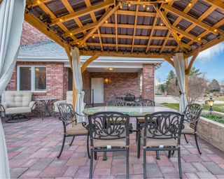wooden pergola on a patio with curtains and lighting around the top