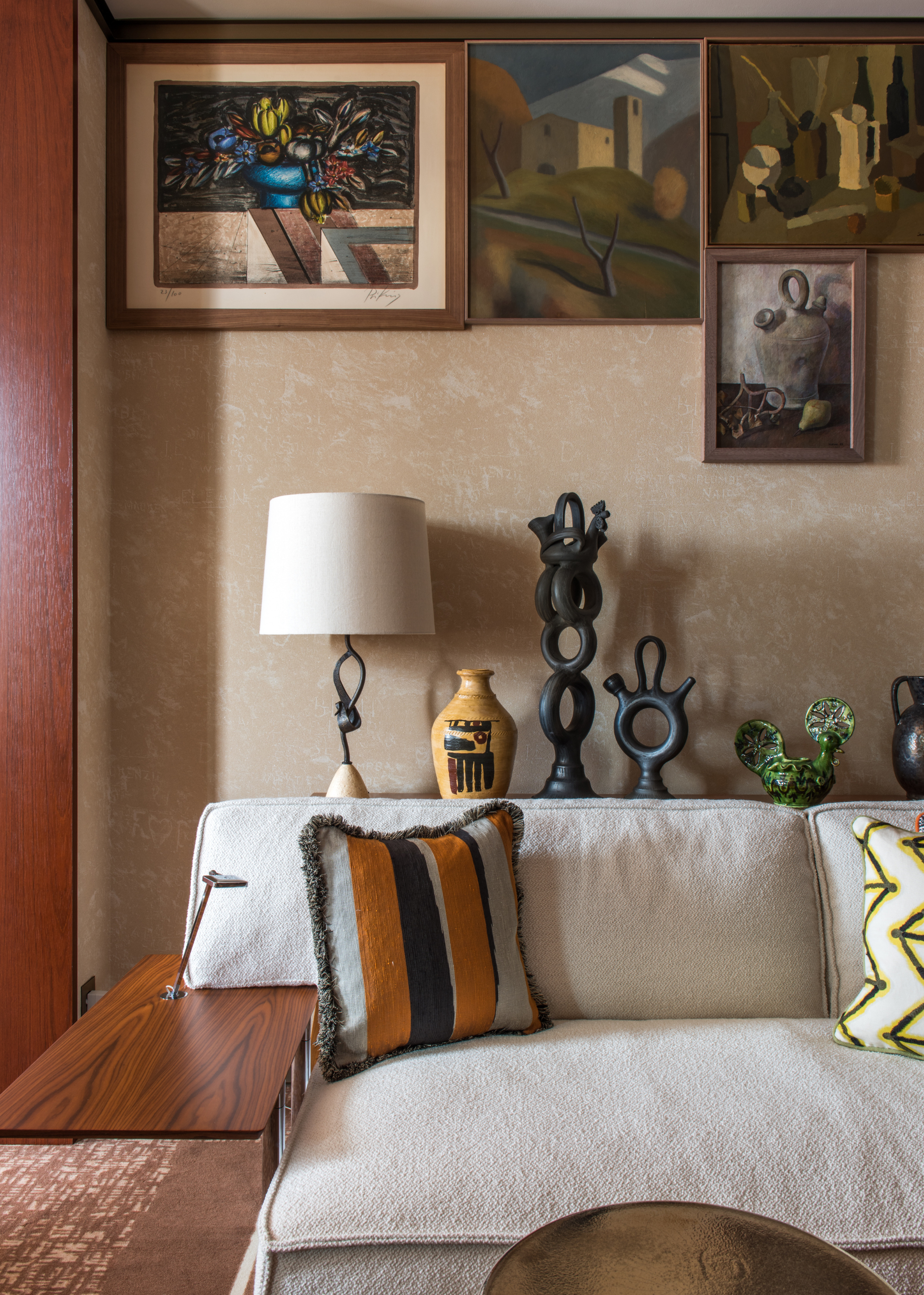 A corner of a hotel room with a plush muted couch and colorful, patterned cushions alongside a set of sculpted ceramics