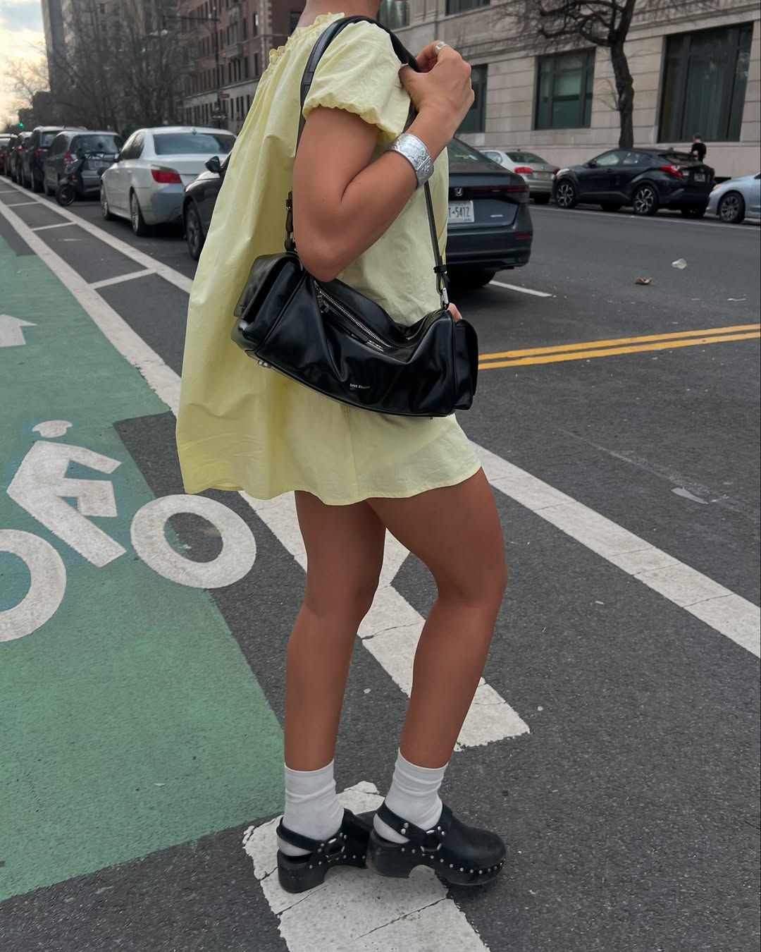 woman wearing yellow mini dress with black clogs and socks in nyc summer outfit