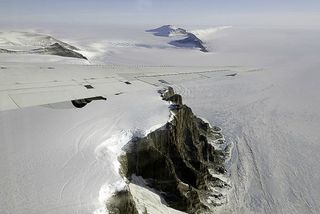 The tip of the wing of a DC-8 plane, part of NASA's IceBridge mission, cuts across a dramatic view of Antarctica's Theron Mountains in October 2011.