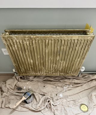 Gold radiator being painted on a green wall