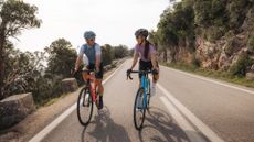 Two riders are cycling up a road climb