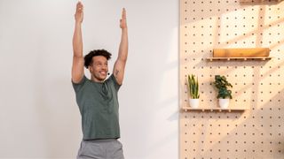 man performing arm circles with arms overhead in a studio setting