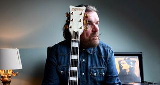 Billy Duffy is photographed at home with his new signature Falcon, which was launched by Gretsch on 13 November 2024 and is finished in Vintage White with gold hardware.