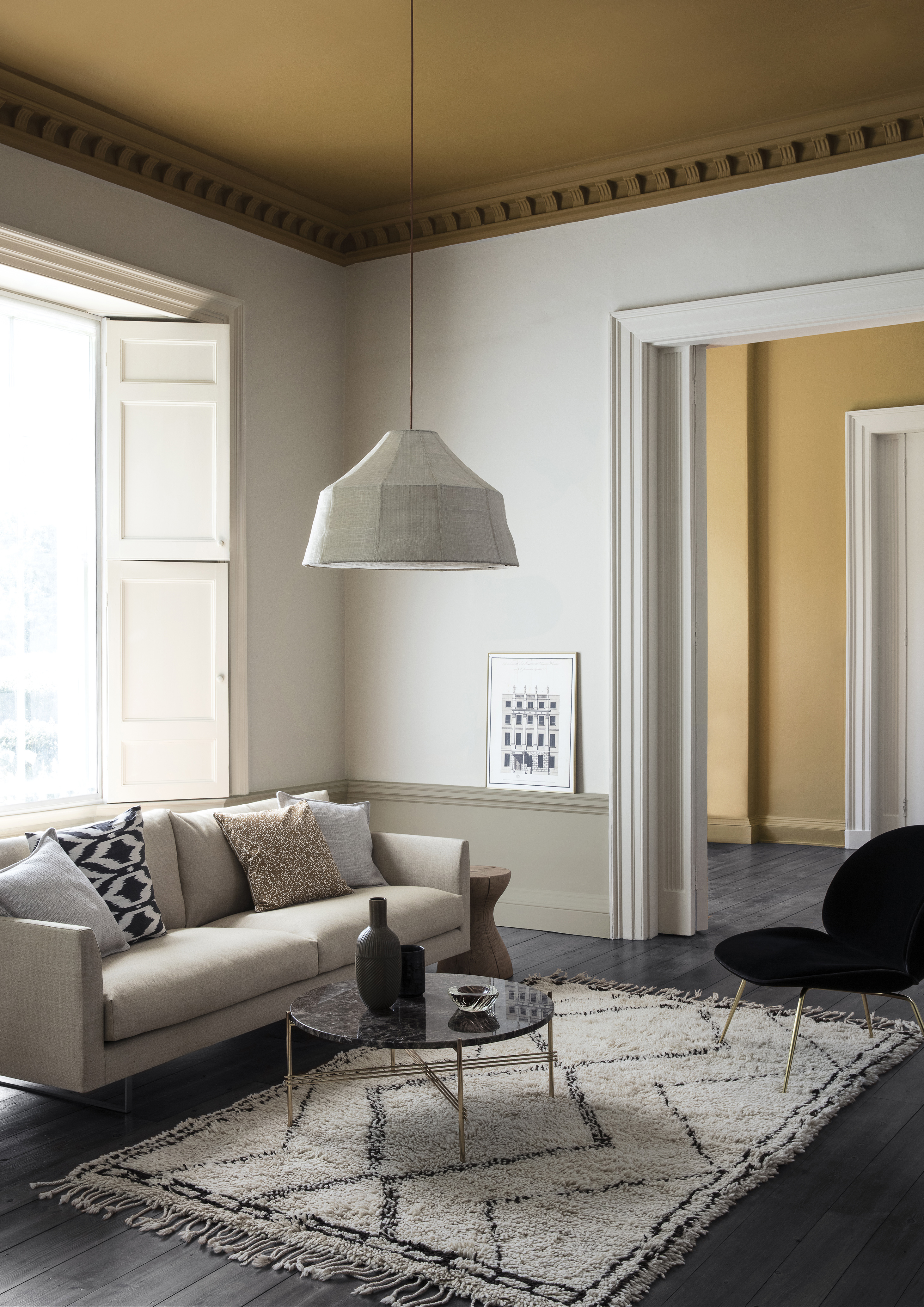 A living room with a neutral colour scheme contrasted with a mustard yellow ceiling.