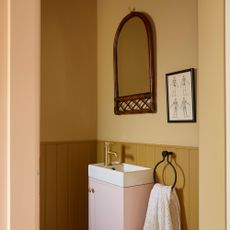 cloakroom bathroom in retro house with yellow walls and panelling and pink vanity