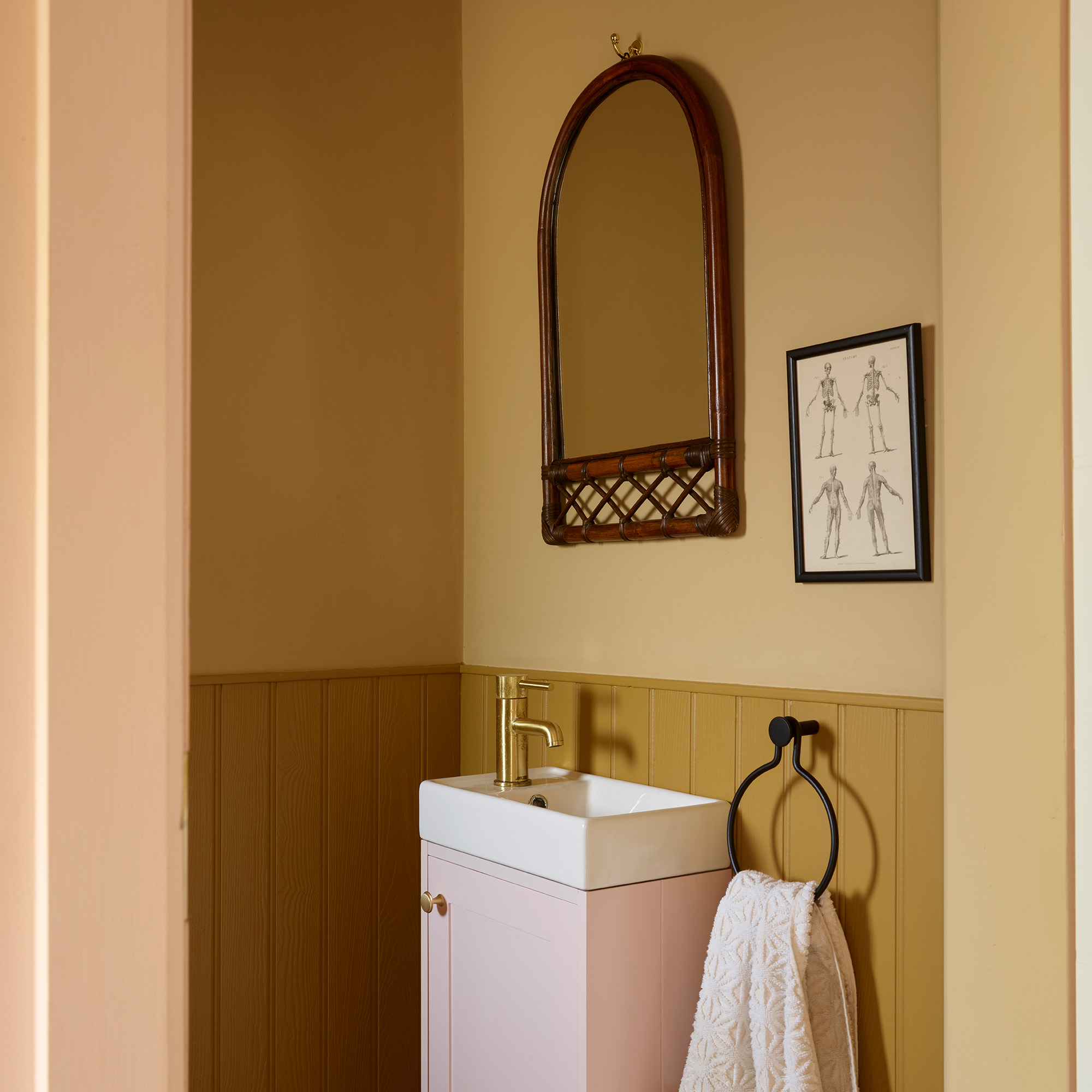 cloakroom bathroom in retro house with yellow walls and panelling and pink vanity