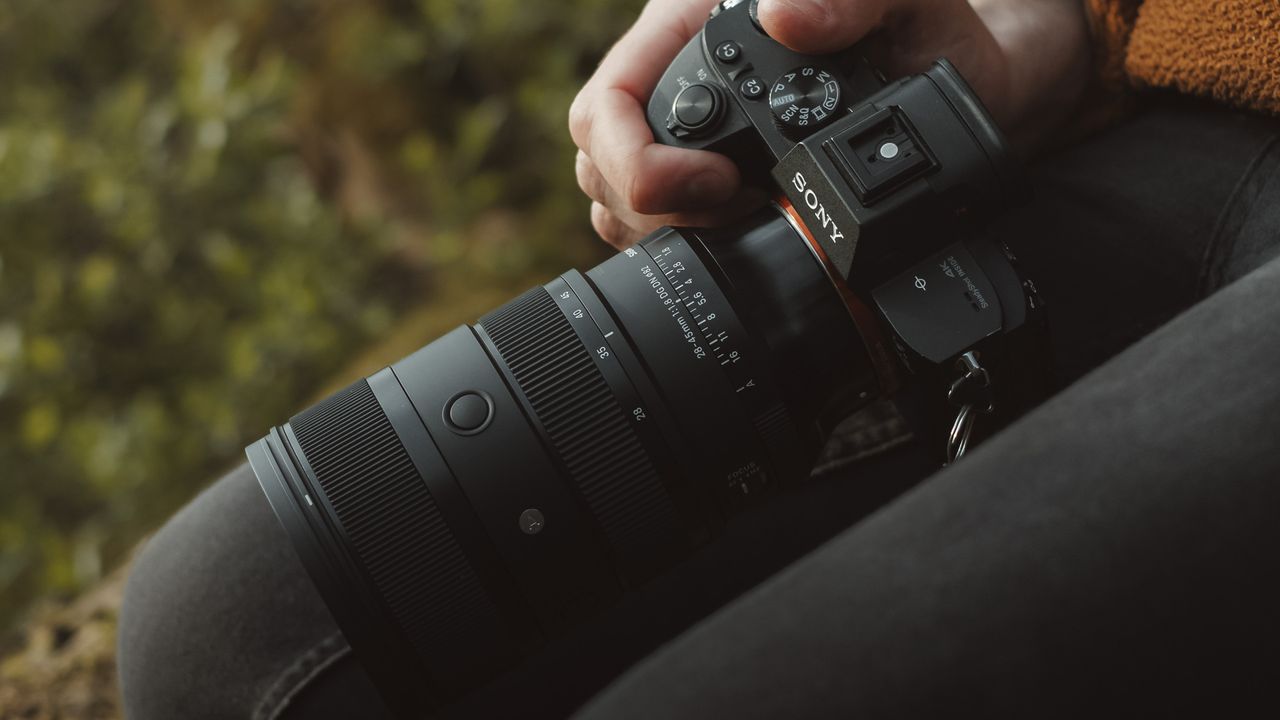 Sigma 28-45mm F1.8 lens mounted on a Sony camera being held by a photographer