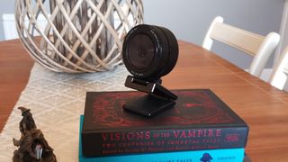 Bästa webbkamera: En svart Razer Kiyo Pro-webbkamera står på två böcker staplade på ett köksbord i trä.