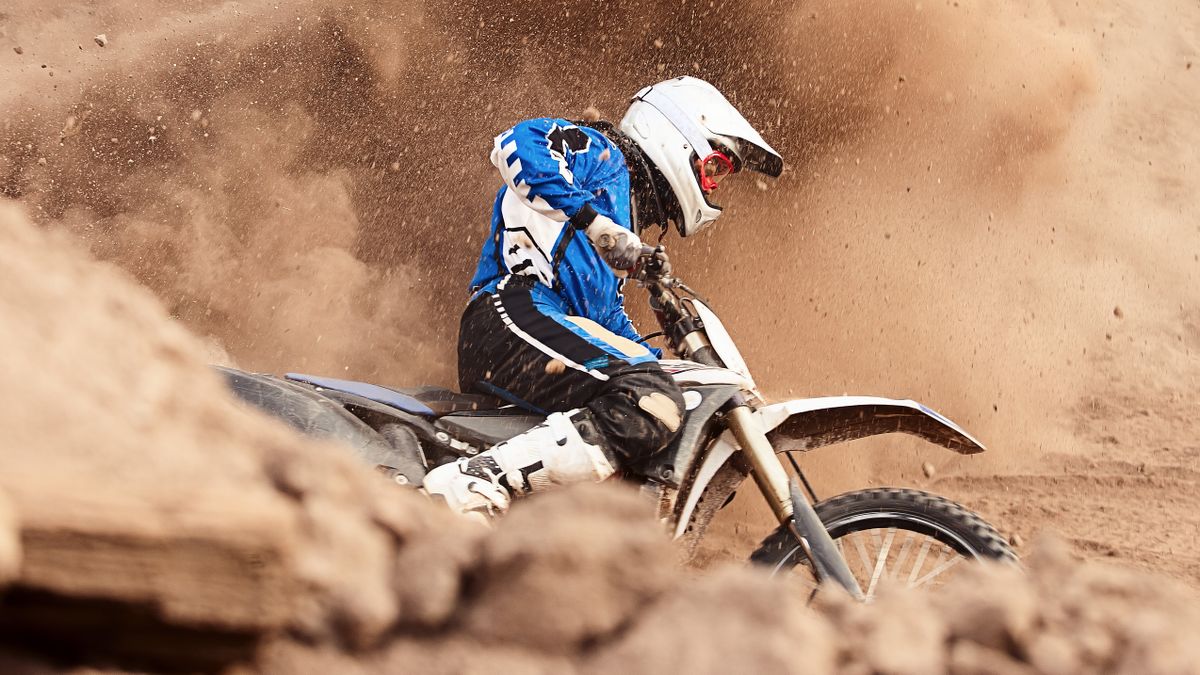 Man making turn on dirt bike in cloud of dust