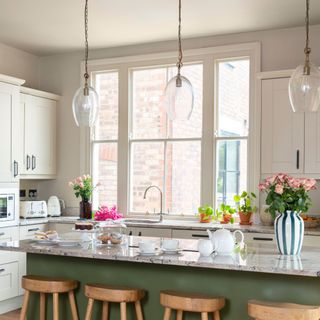 Large window in kitchen, with light units and large central island with pendant lights above