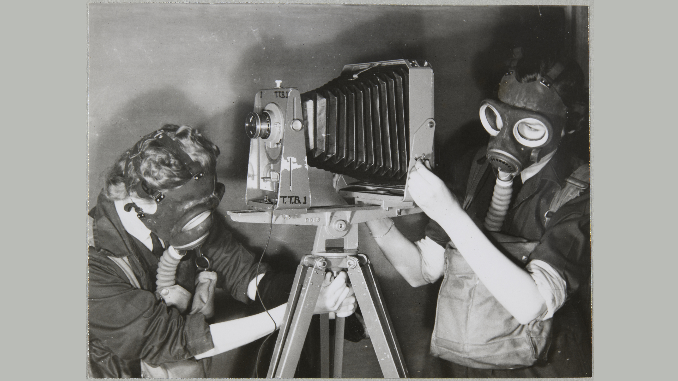 Two Women's Auxiliary Air Force (WAAF) trainees practising photography whilst wearing gas masks to simulate working under active service conditions, during training at No.2 School of Photography in Blackpool