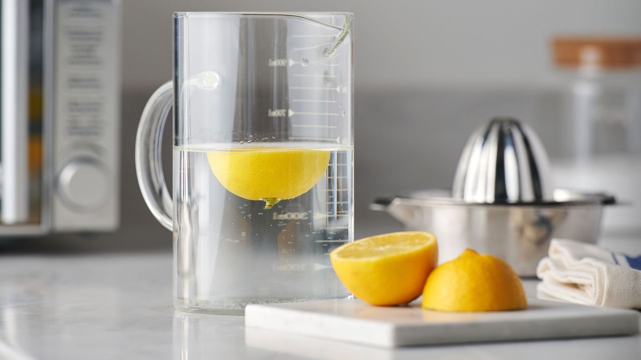 Jug of water with lemons in it, and lemons on a chopping board next to it