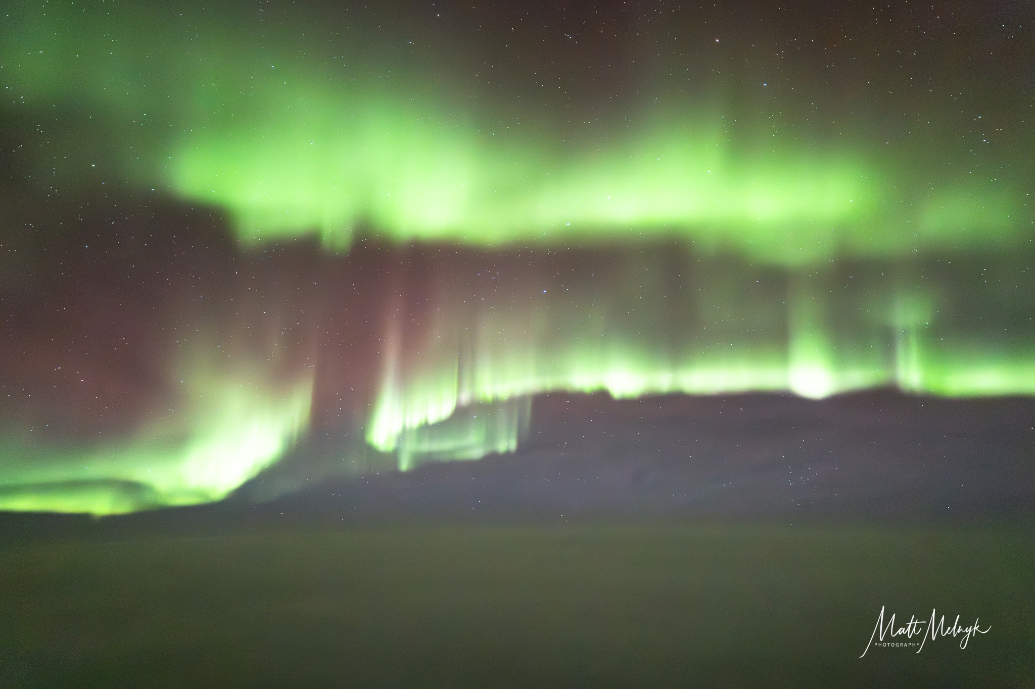 Ribbons of green light fill the sky and the northrn lights stretch on across the scene.