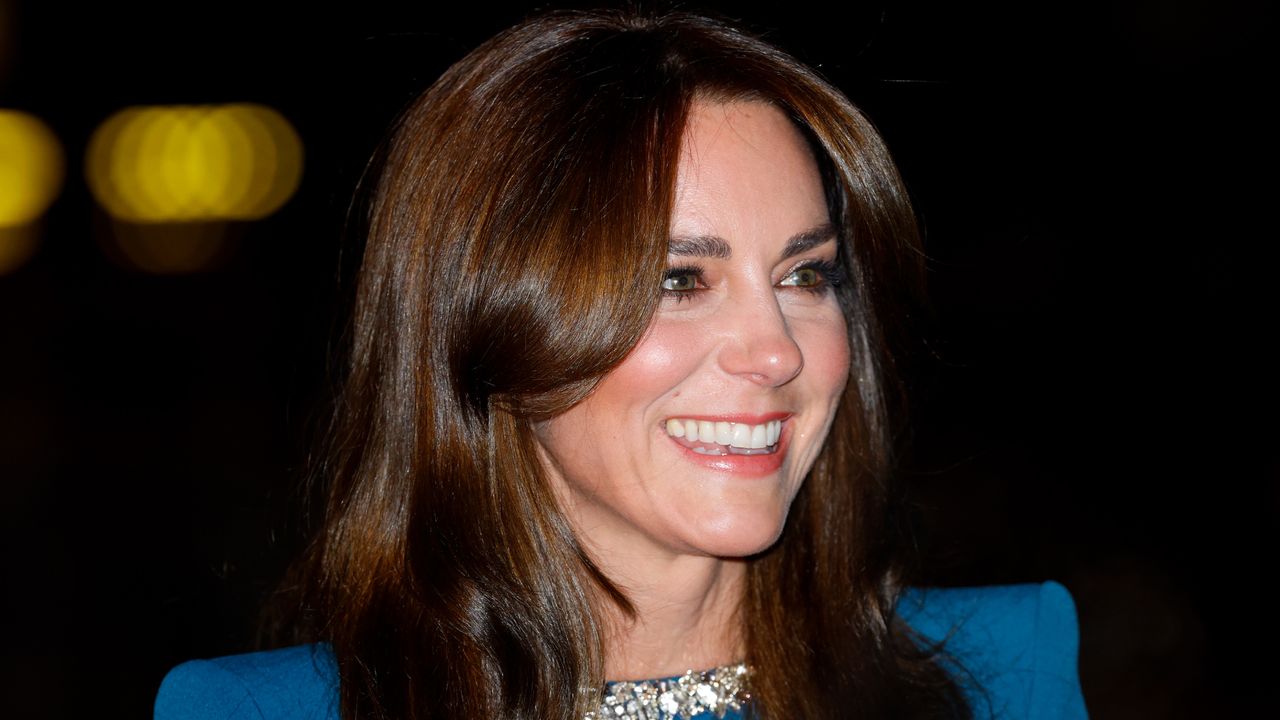 A shoulders up photo of Kate Middleton wearing a blue evening gown with a crystal neckline and smiling