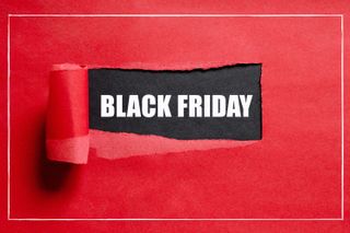 Red sheet of paper with a tear in the middle through which you can see the words Black Friday in white on a black background