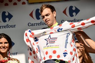 Dion Smith puts on the best climber's polka dot jersey on the podium after the third stage