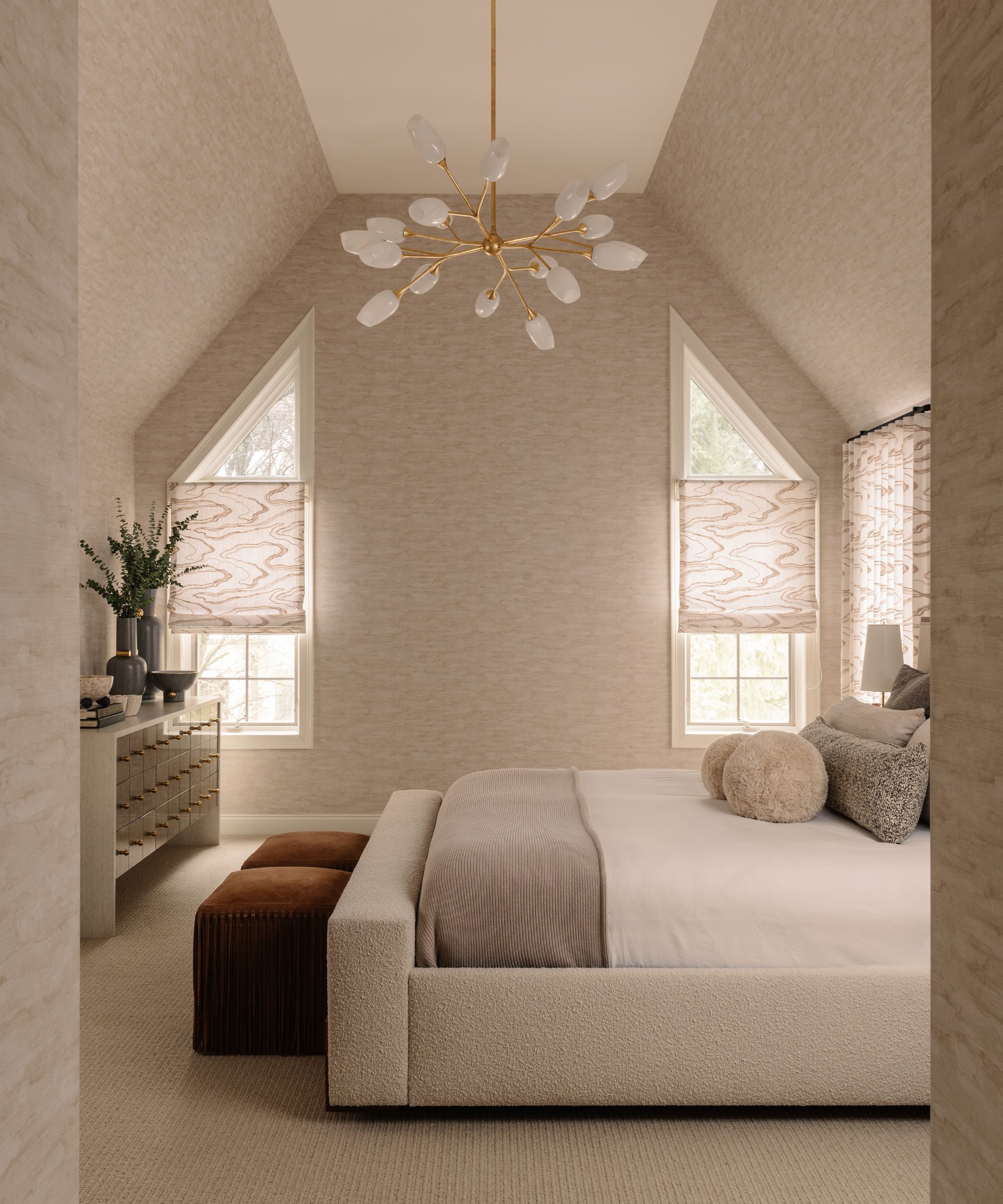 Neutral bedroom with subtly patterned wallpaper and high ceilings and a boucle bed dressed in white and gray bedding