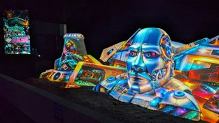 A colorful cyborg sand sculpture brought to life by projection. 