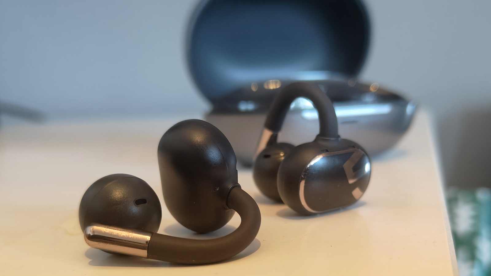 The Soundpeats Clip1 buds on a table next to the case.