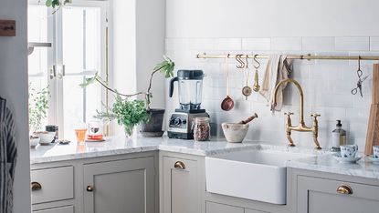 a small beige kitchen with brass hardware, a Belfast sink, storage solutions and a small countertop