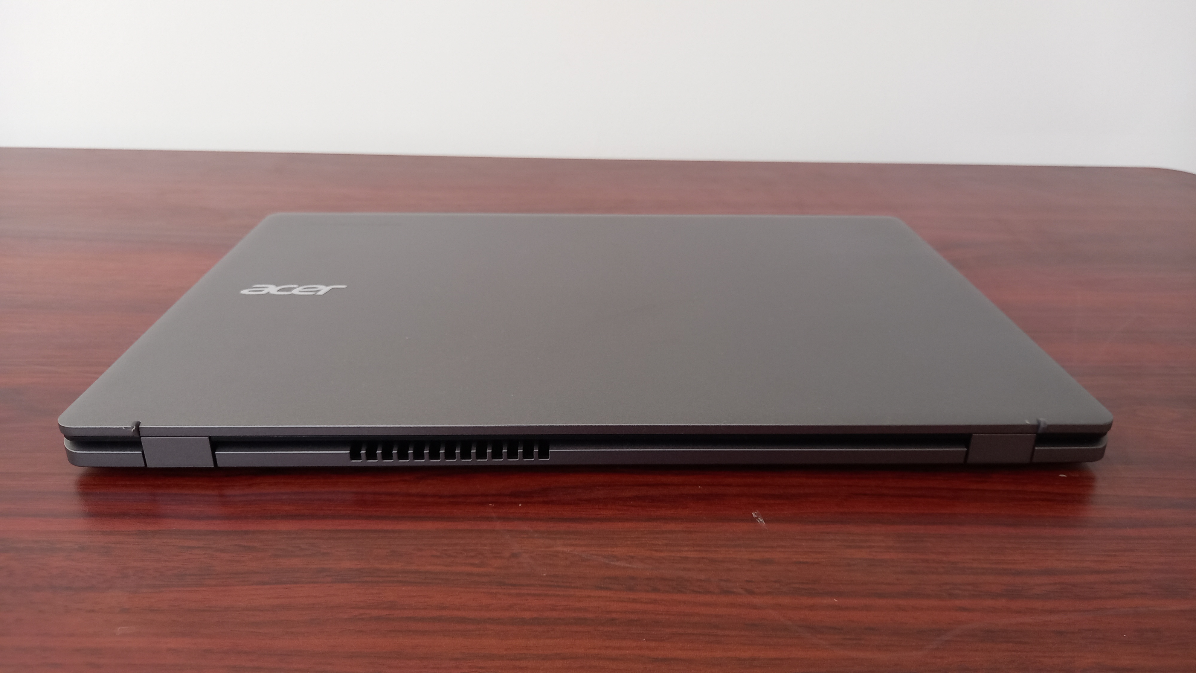 An Acer Chromebook Plus 515 on desk showing abstract painted wallpaper on its screen