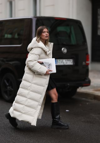 woman wearing long puffer coat,, skirt, and boots