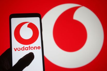 Vodafone logo displayed on a smartphone in a silhouette of a hand