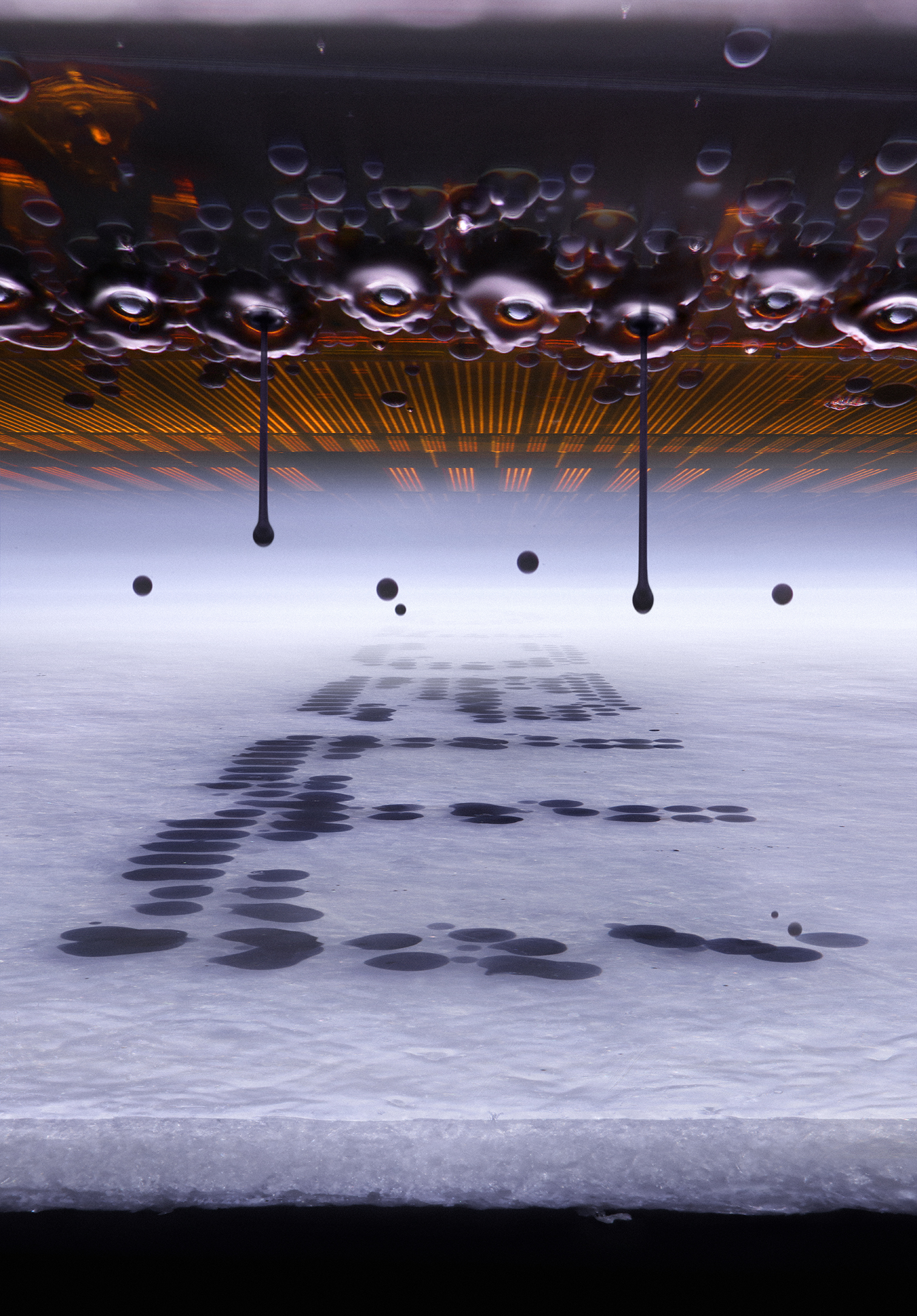 Microscopic view of an inkjet printer depositing ink onto paper: water droplets and elongated drips on a reflective surface, casting dark shadows across the paper that looks like ice