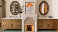 A bathroom fireplace flanked by two wooden vanity units
