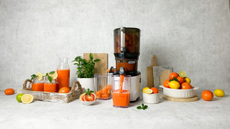 Kuvings Auto10 Hands-Free Juicer surrounde by fresh oranges, lemons and juice