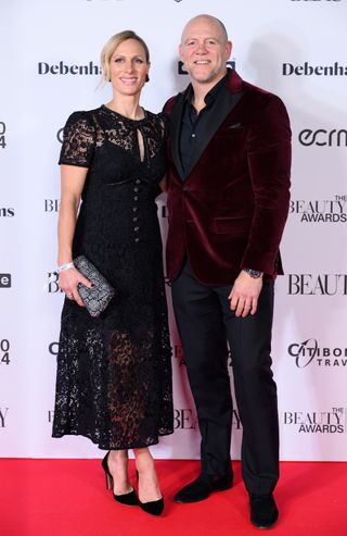 Zara Tindall wearing a black lace dress on the red carpet standing next to husband Mike Tindall