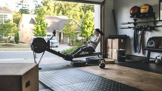 A woman using a rowing machine the home gym she's constructed in her garage