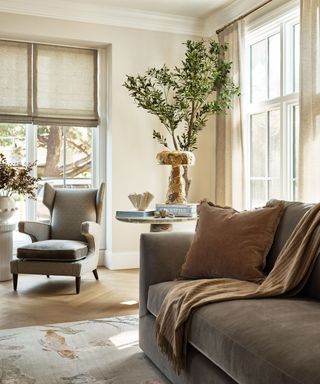 coastal scandifornia living room with a gray velvet couch and a marble side table with antique decor