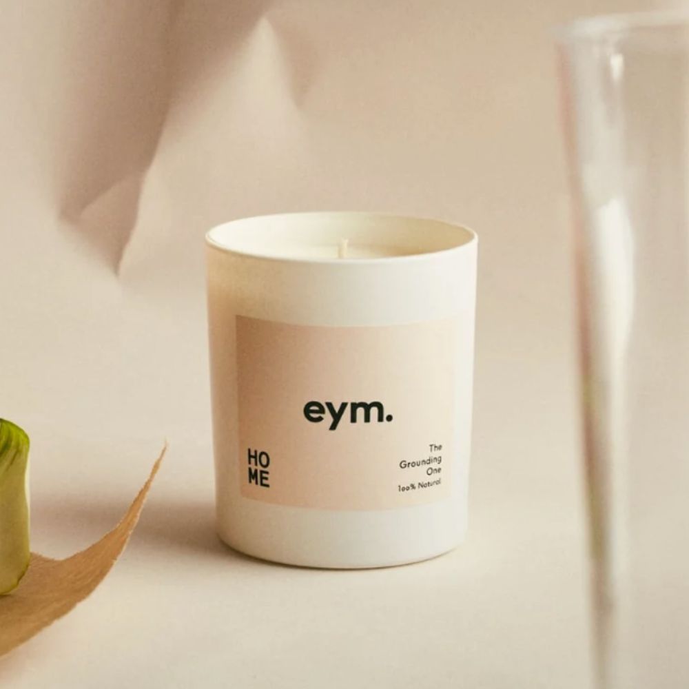 eym candle on crumpled paper background with leaf and glass vase in foreground