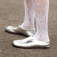 A woman wearing silver flats and white lace socks