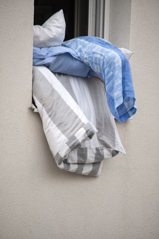 Duvets hanging outside a window to air