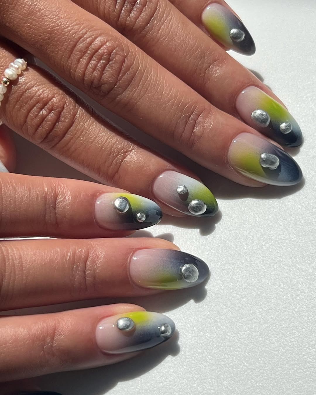 Ombré nails with pops of green and metallic silver 3D accents.