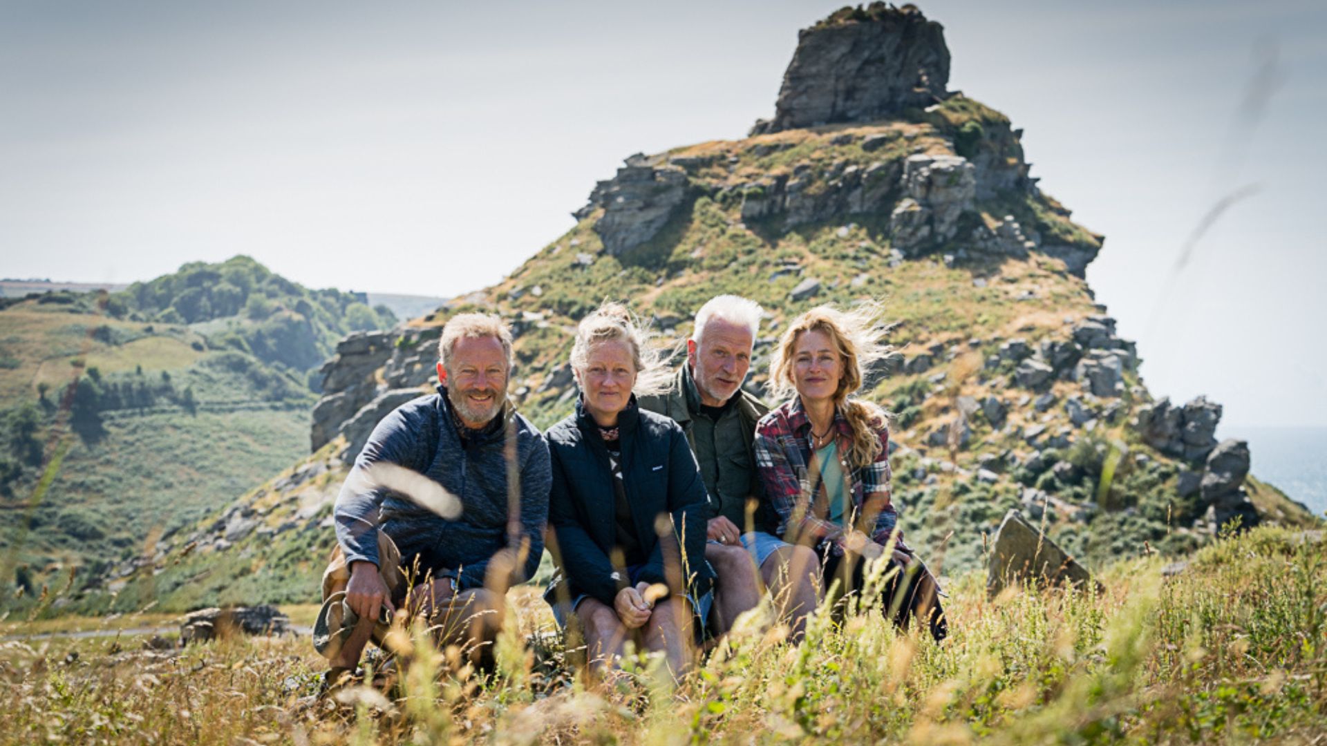 Raynor and Moth with Jason Isaacs and Gillian Anderson sitting on grassy hill