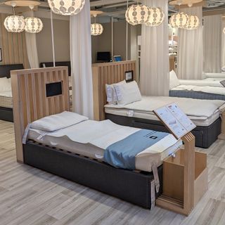 A mattress showroom with a wooden floor and multiple mattress on bed frames