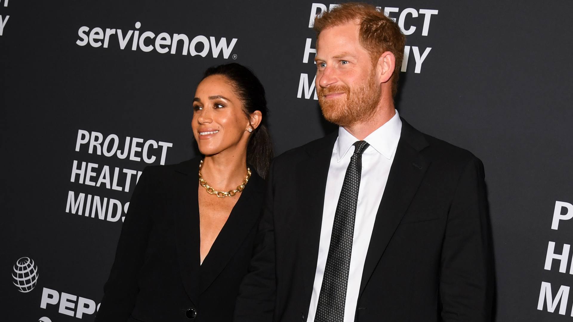 Prince Harry and Meghan Markle wearing black suits
