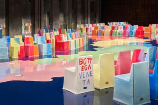Bottega Veneta S/S 2023 show set with multicoloured chairs beside runway