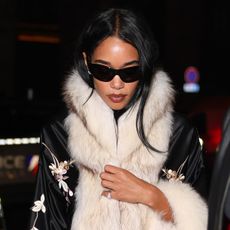 Laura Harrier at PFW wearing a Conner Ives embroidered fur robe with capri pants and pumps