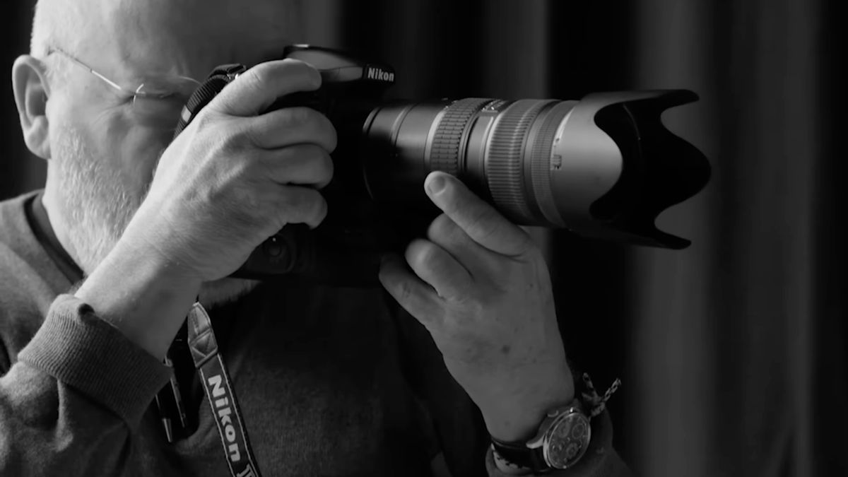 A black and white image of Peter Lindbergh holding the Nikon D810