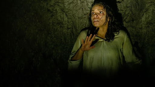 A woman in the dark looking scared in Barbarian