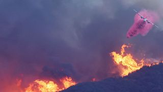 A firefighting aircraft drops Phos-Chek pink fire retardant on Pacific Palisades on Jan. 7