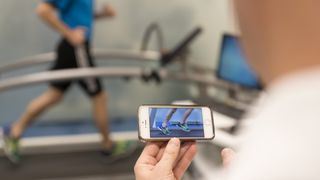 Specialist recording person running on treadmill using a phone