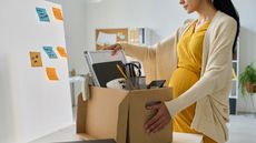 A pregnant woman packs up her desk at the office.