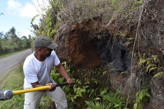Comorian government geologist Hamidi Soulé prepares to crack into a roadside outcropping in search of quartzite.