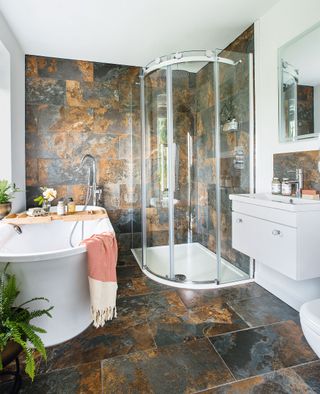 bathroom with large stone effect tiles and roll-top bath and quadrant shower